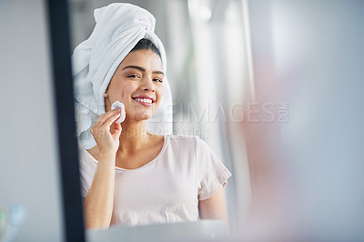 Buy stock photo Shot of a beautiful young woman cleaning her face with cotton wool in the bathroom at home