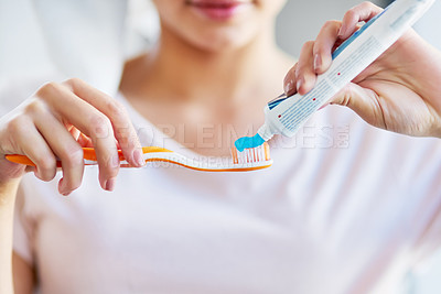 Buy stock photo Closeup shot of a young woman squeezing toothpaste onto her toothbrush in the bathroom at home