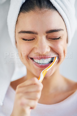 Buy stock photo Shot of a beautiful young woman brushing her teeth in the bathroom at home