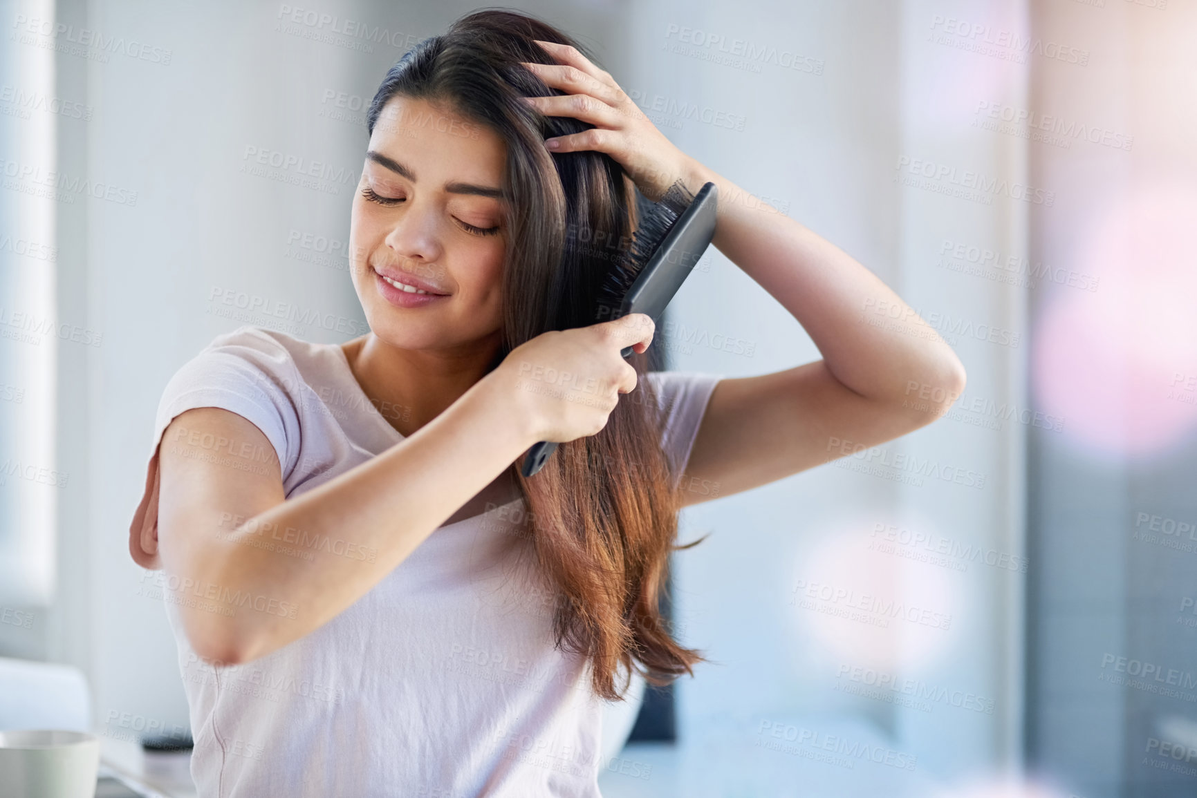 Buy stock photo Shot of a beautiful young woman brushing her hair in the bathroom at home