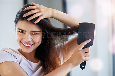 Buy stock photo Portrait of a beautiful young woman brushing her hair in the bathroom at home