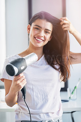 Buy stock photo Portrait of a beautiful young woman blowdrying her hair in the bathroom at home