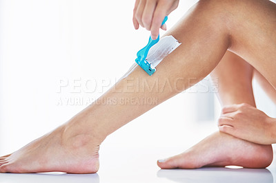 Buy stock photo Closeup shot of an unrecognizable woman shaving her legs in the bathroom at home