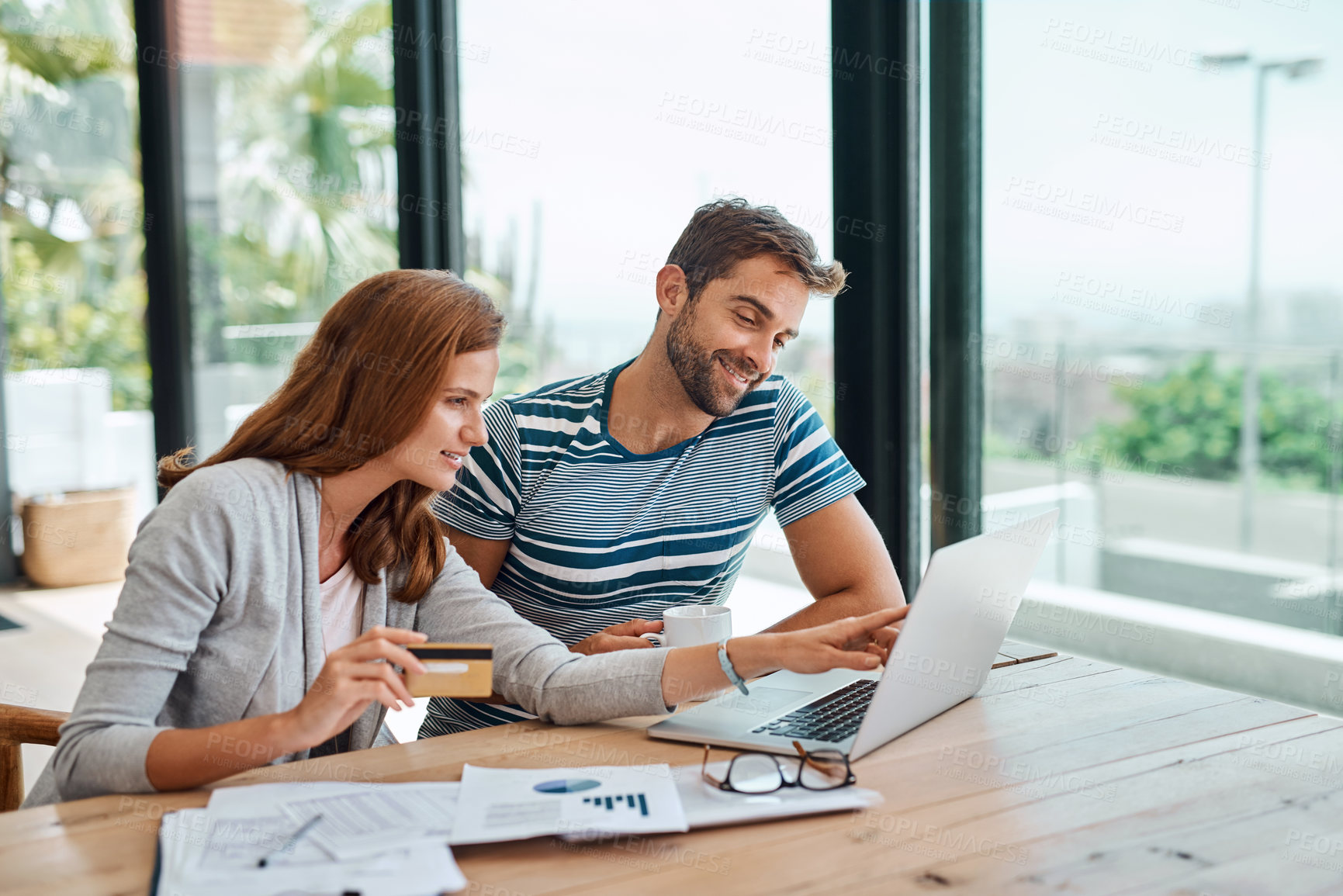 Buy stock photo Shot of a young couple working on their household budget and paying bills online