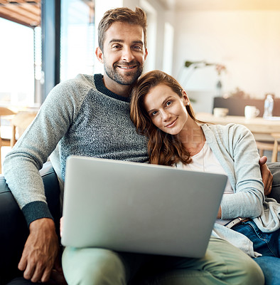 Buy stock photo Portrait of an affectionate young couple using a laptop while relaxing on their sofa at home