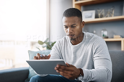 Buy stock photo Scroll, tablet and man on couch search social media, reading email or streaming video on subscription service. Thinking, internet and networking, person with serious face and research online on sofa
