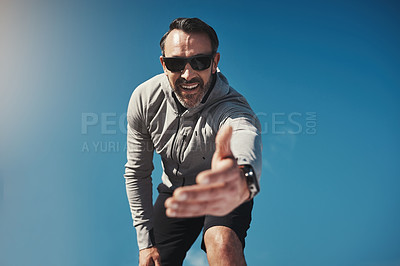 Buy stock photo Low angled portrait of a middle aged man standing on a rock and reaching out his hand