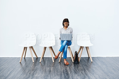 Buy stock photo Full length studio shot of an attractive young businesswoman sitting down on a chair and using her laptop