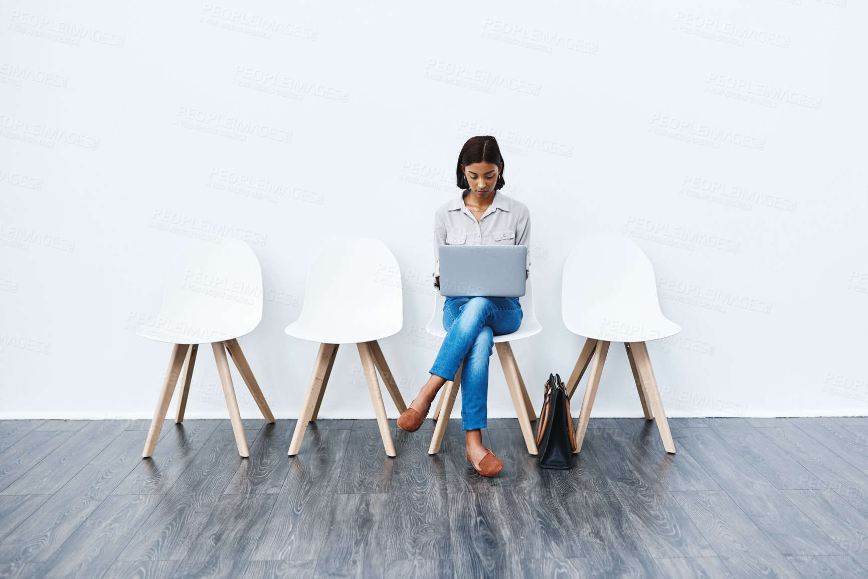 Buy stock photo Full length studio shot of an attractive young businesswoman sitting down on a chair and using her laptop