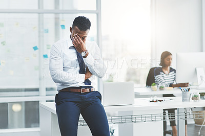 Buy stock photo Shot of a young businessman standing in an office looking stressed out