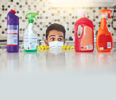Buy stock photo Cropped shot of a handsome young man peaking over the kitchen counter while cleaning his home