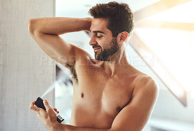 Buy stock photo Cropped shot of a handsome young man applying deodorant to his under his arms in the bathroom