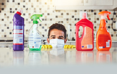 Buy stock photo Cropped portrait of a handsome young man peaking over the kitchen counter while cleaning his home