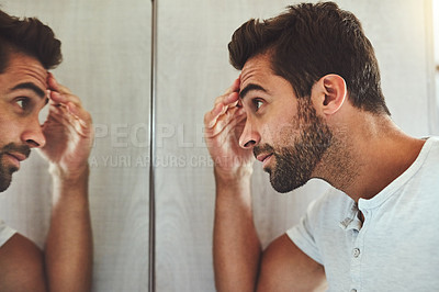 Buy stock photo Cropped shot of a handsome young man looking at himself closely in the mirror at home during the day