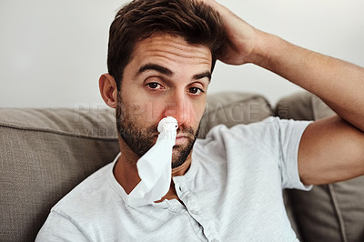 Buy stock photo Cropped portrait of a young man with a tissue in his nose due to sinus related problems