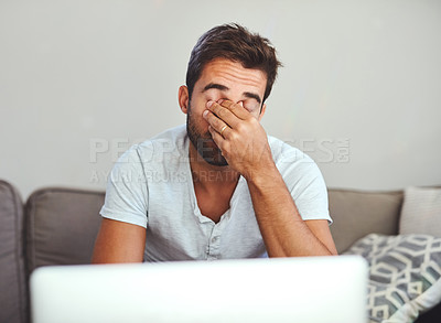 Buy stock photo Cropped shot of a handsome young man looking stressed while working on his laptop at home