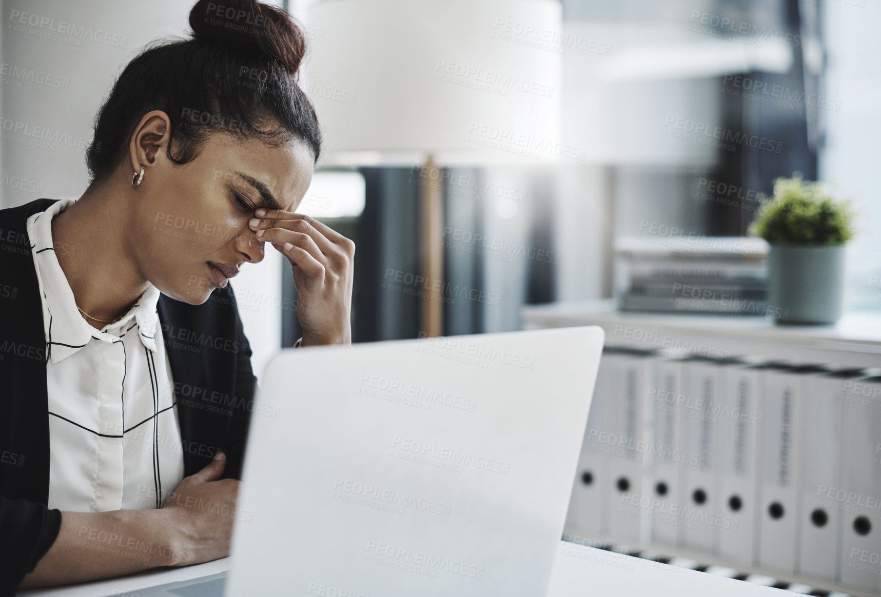 Buy stock photo Shot of a young businesswoman looking stressed while working at her desk in a modern office