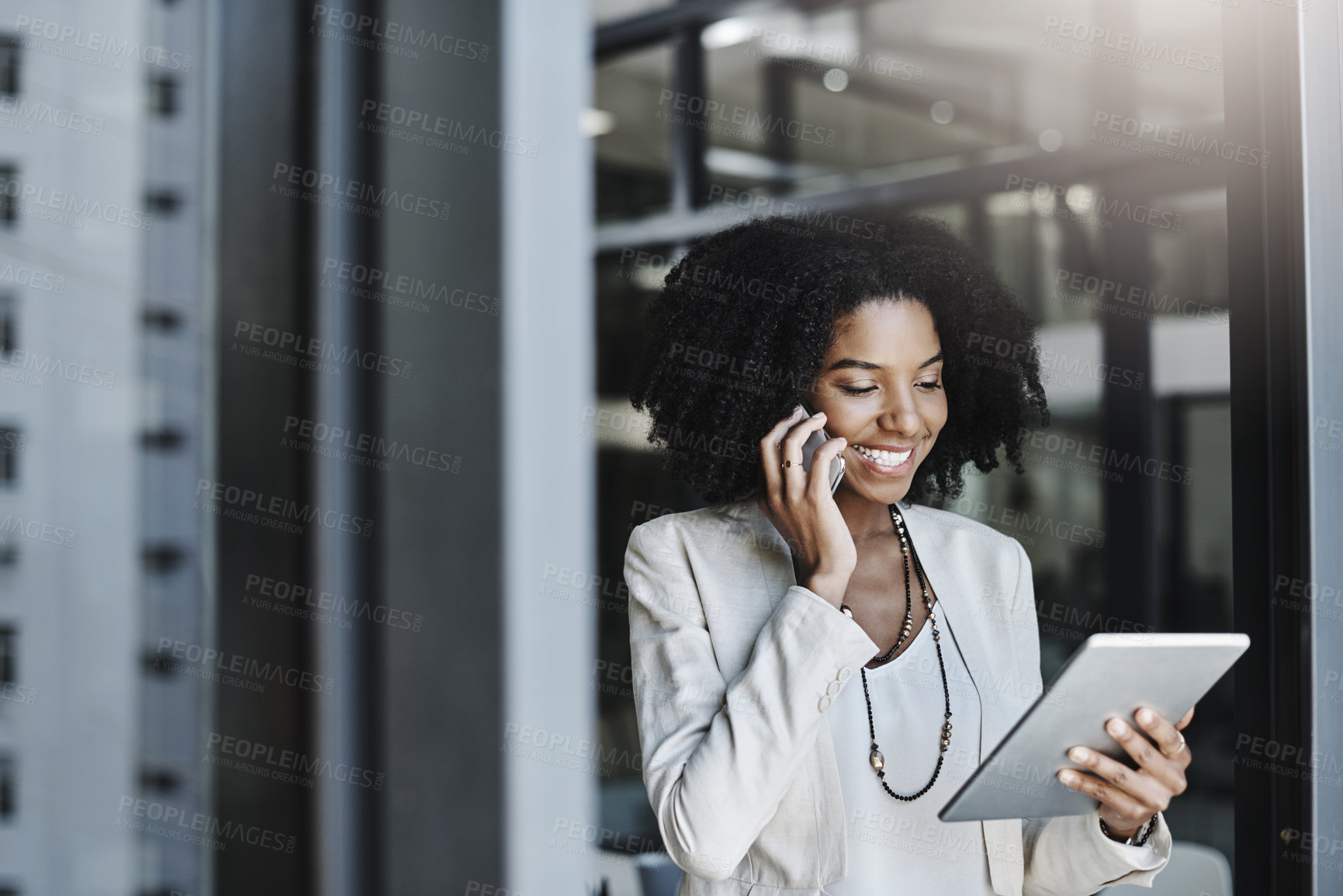 Buy stock photo Shot of a young businesswoman talking on a cellphone while holding a digital tablet in her office