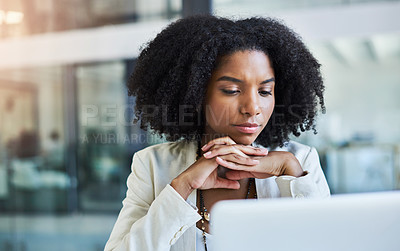 Buy stock photo Shot of a young businesswoman sitting down and looking at her laptop screen in her office