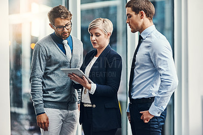Buy stock photo Cropped shot of three businesspeople working on a digital tablet in a busy office