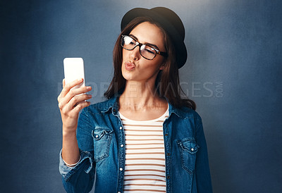 Buy stock photo Studio shot of a beautiful young woman taking a selfie against a blue background