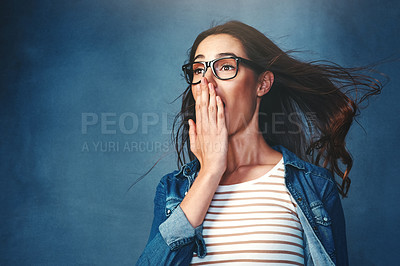 Buy stock photo Studio shot of a young woman with air being blown in her face against a blue background