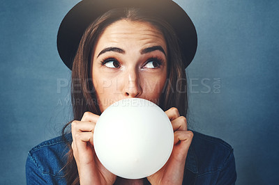 Buy stock photo Studio shot of an attractive young woman blowing up a balloon against a blue background