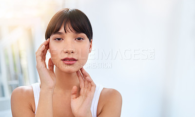 Buy stock photo Portrait of a cheerful attractive young woman touching her face while looking into a mirror at home during the day