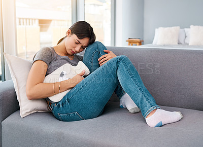 Buy stock photo Stomach pain, stress or girl on sofa with hot water bottle for pms gas, constipation or period crisis at home. Tummy, digestion or anxiety in living room with heating pad for endometriosis or pcos