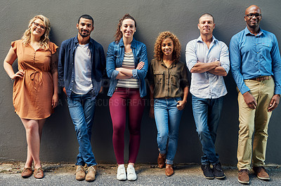 Buy stock photo Portrait of a group of people standing together against a wall outside
