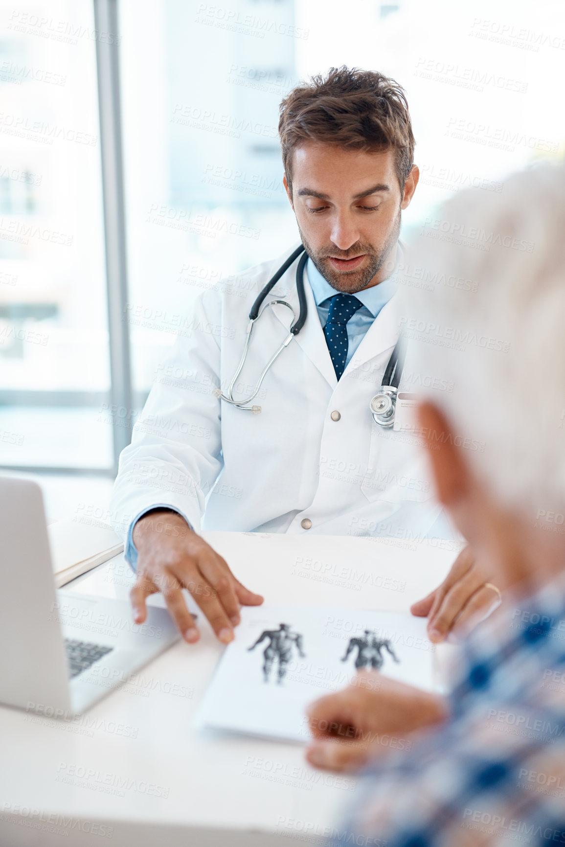 Buy stock photo Cropped shot of a handsome young male doctor consulting with a patient in his office