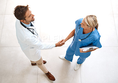 Buy stock photo High angle shot of two healthcare practitioners shaking hands in the hospital foyer
