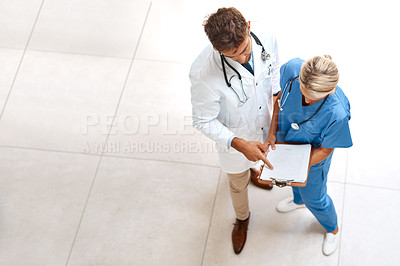 Buy stock photo High angle shot of two healthcare practitioners looking over documents in the hospital