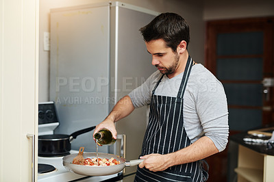 Buy stock photo Cropped shot of a handsome young man cooking in the kitchen