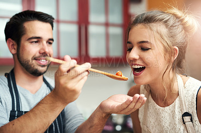 Buy stock photo Cropped shot of a handsome young man feeding his girlfriend food that he has made at home