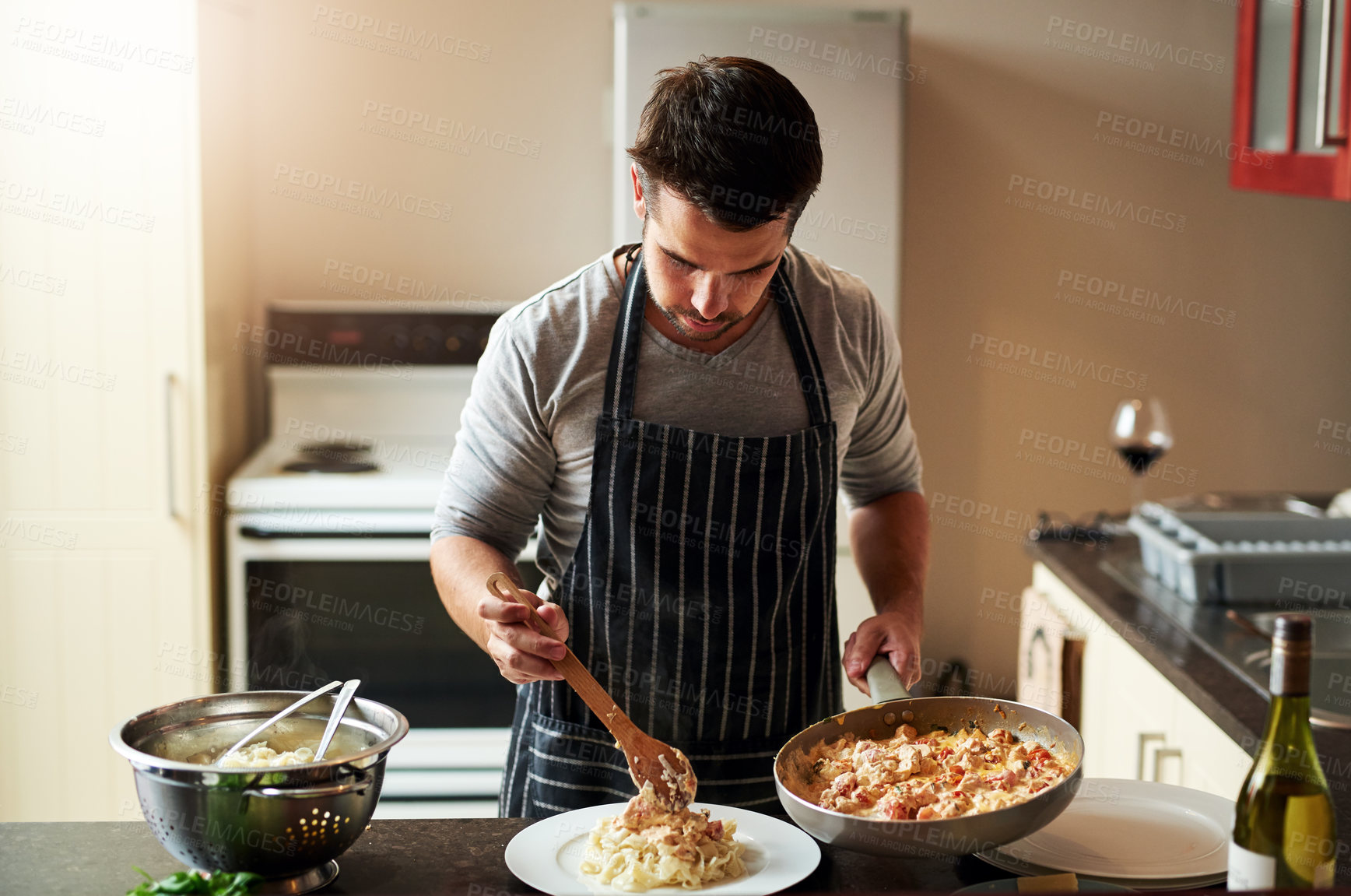 Buy stock photo Cropped shot of a handsome young man dishing food in the kitchen at home