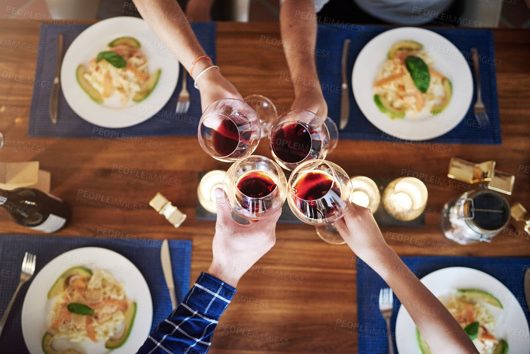 Buy stock photo High angle shot of a group of unrecognizable people toasting at the dining room table at home