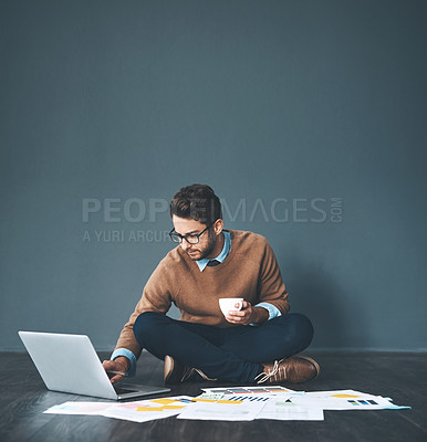 Buy stock photo Studio shot of a young businessman working with a laptop and paperwork against a grey background