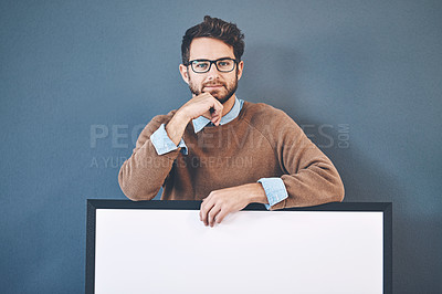 Buy stock photo Young man standing behind an empty sign with copyspace. Smiling, attractive and smart male holding a blank board announcement for marketing. Handsome guy with a poster for an advert, banner or news.
