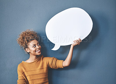 Buy stock photo Young woman holding a speech bubble against a grey background in a studio. Portrait of a casual, happy and smiling female holding copy space empty shape for social media, chat and voice or message.