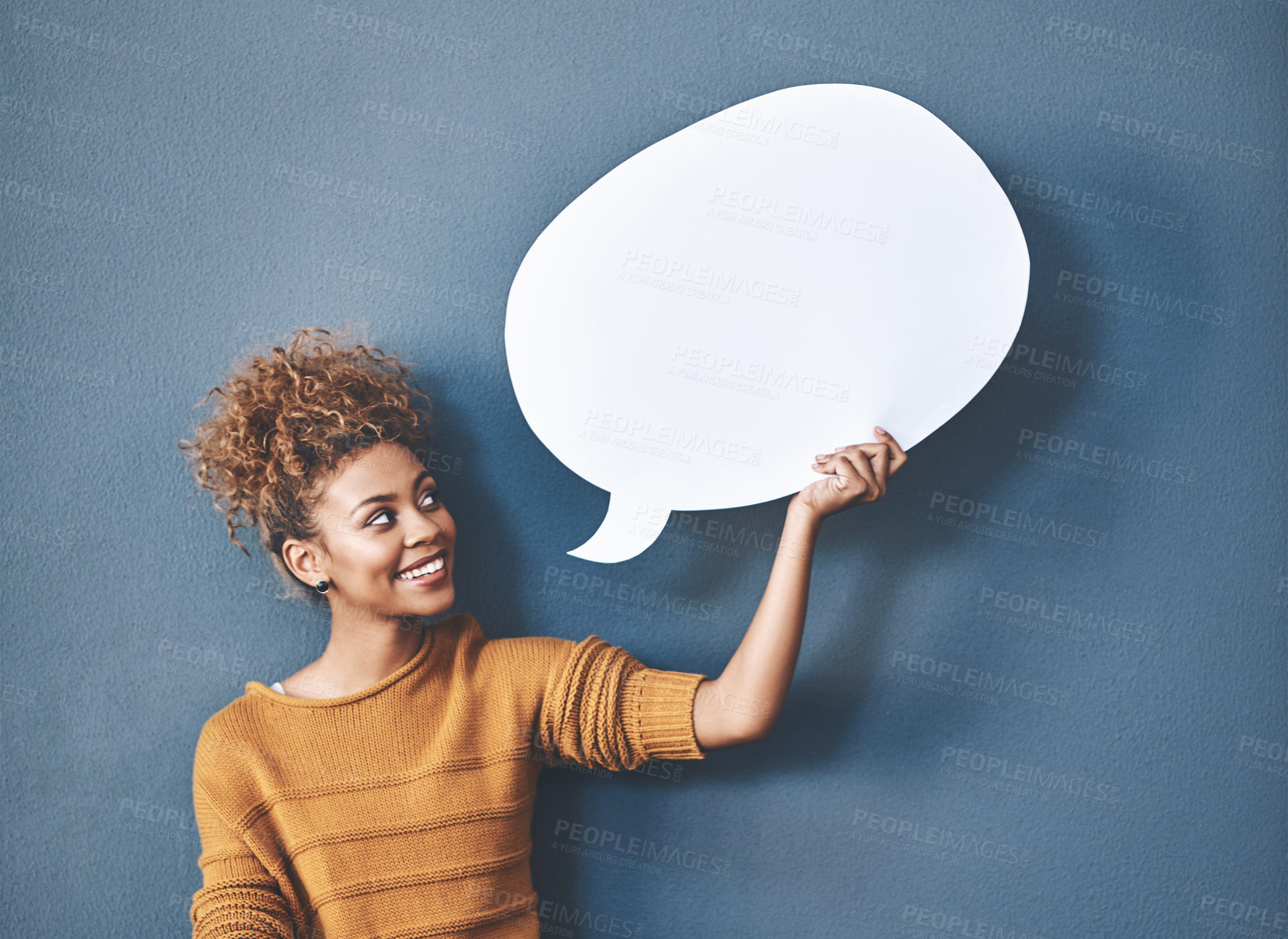 Buy stock photo Young woman holding a speech bubble against a grey background in a studio. Portrait of a casual, happy and smiling female holding copy space empty shape for social media, chat and voice or message.