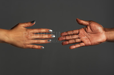 Buy stock photo Studio shot of two unrecognizable people reaching out their hands towards each other against a grey background