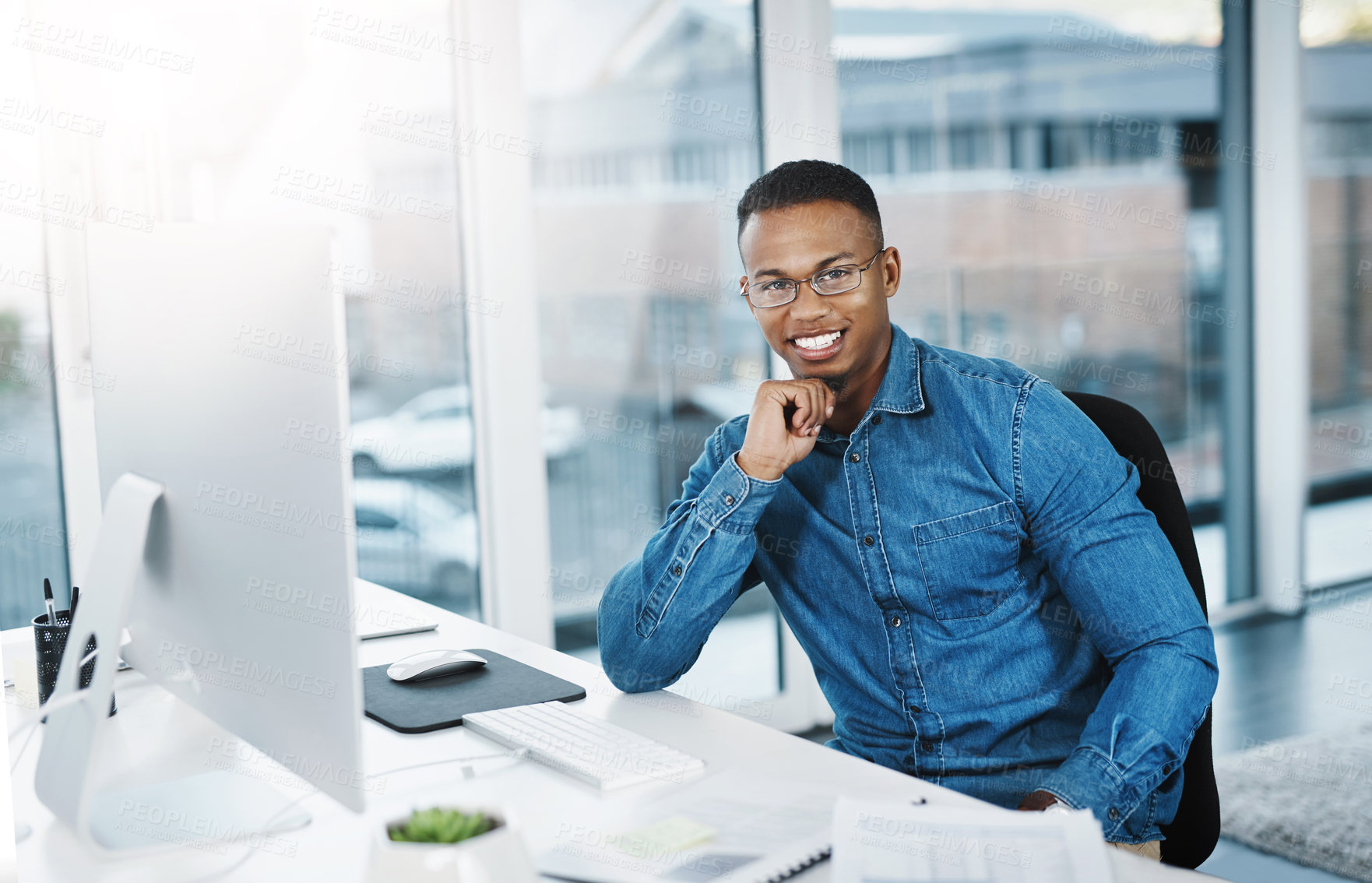 Buy stock photo Portrait, smile and businessman in modern office with laptop, paperwork and happy at desk. Black man, pride and technology in workplace for internship, journalist and research for startup company