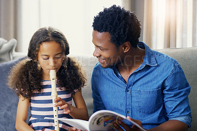 Buy stock photo Shot of a young father teaching his daughter how to play the recorder at home