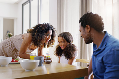 Buy stock photo Shot of a young family celebrating a birthday together in the kitchen at home