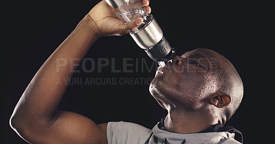 Buy stock photo Studio shot of a young sportsman drinking from a water bottle against a dark background