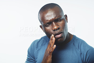 Buy stock photo Studio shot of a young man suffering from a toothache against a grey background
