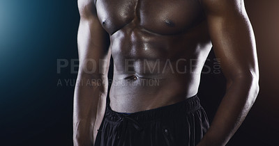 Buy stock photo Studio shot of an unrecognized shirtless male athlete posing against a dark background