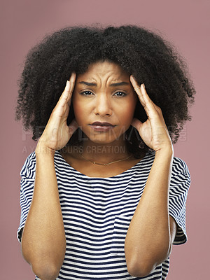 Buy stock photo Shot of a young woman suffering from a headache against a pink background