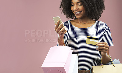Buy stock photo Studio shot of a young woman doing online shopping while carrying shopping bags
